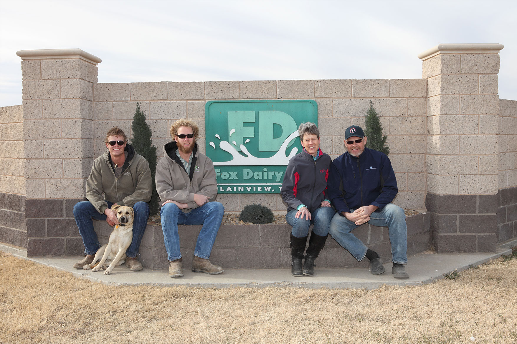 The DeVos family poses in front of the sign for their dairy farm.