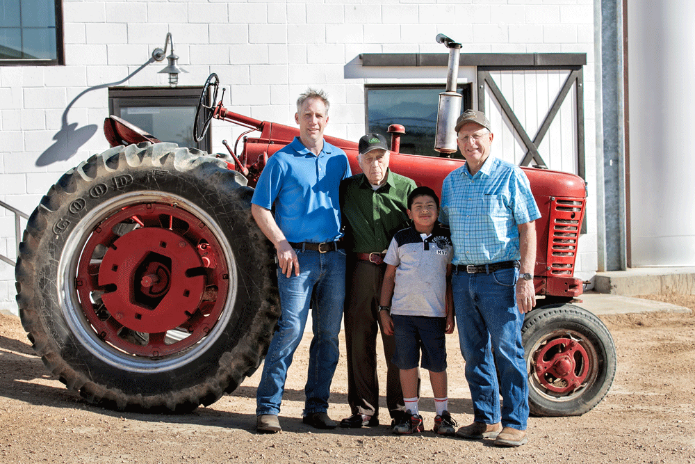 Four generations of Feldpausch men posing for a photo in front of the milking parlor.