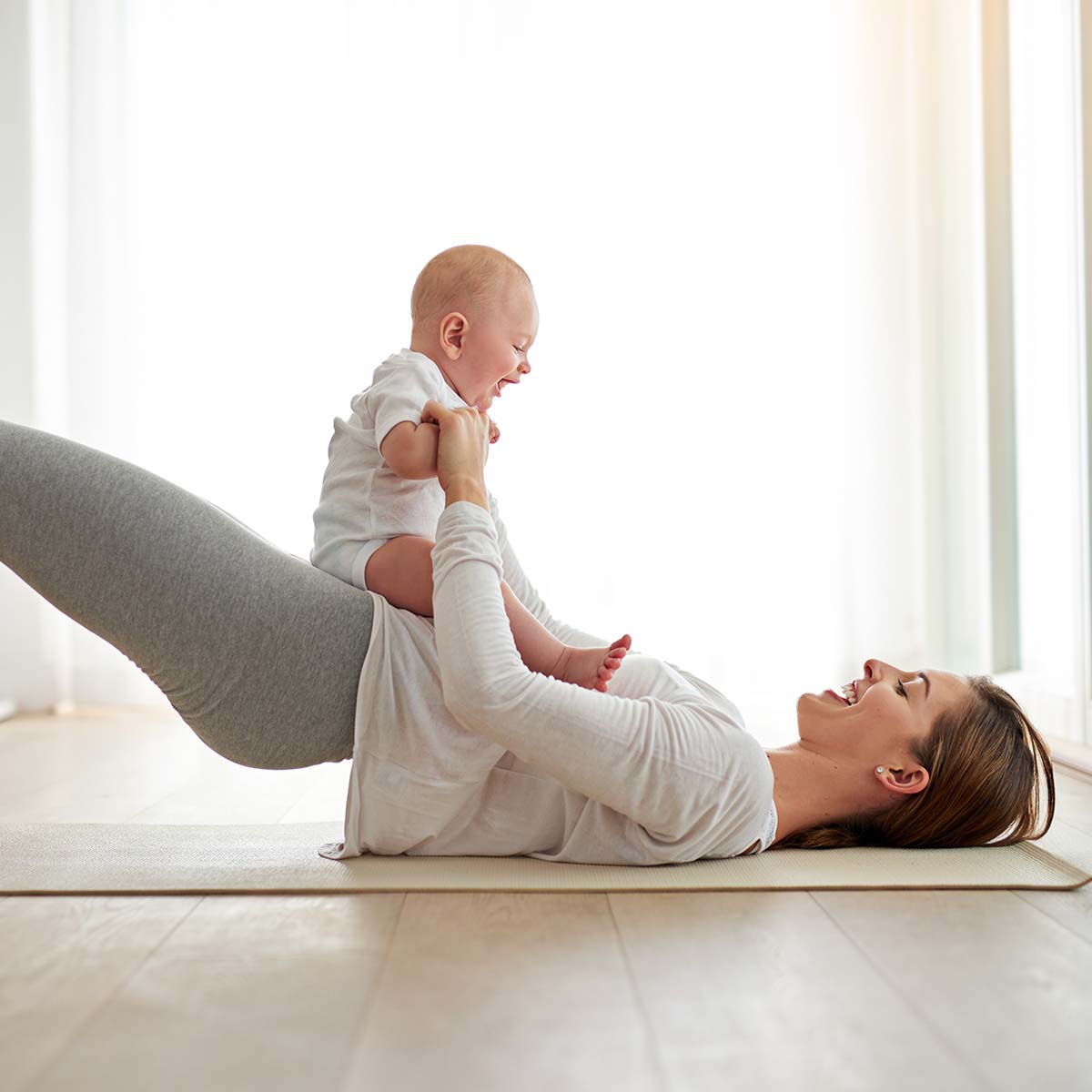 a woman does a glute bridge with her baby