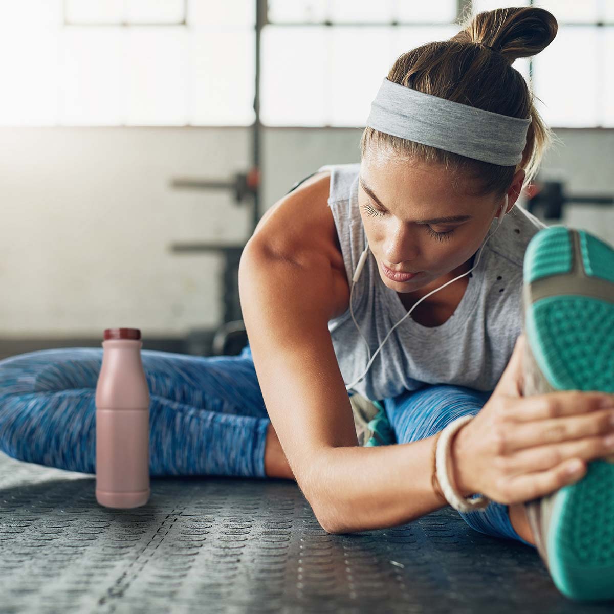 woman in workout clothes stretching her hamstring with a bottle of chocolate milk nearby