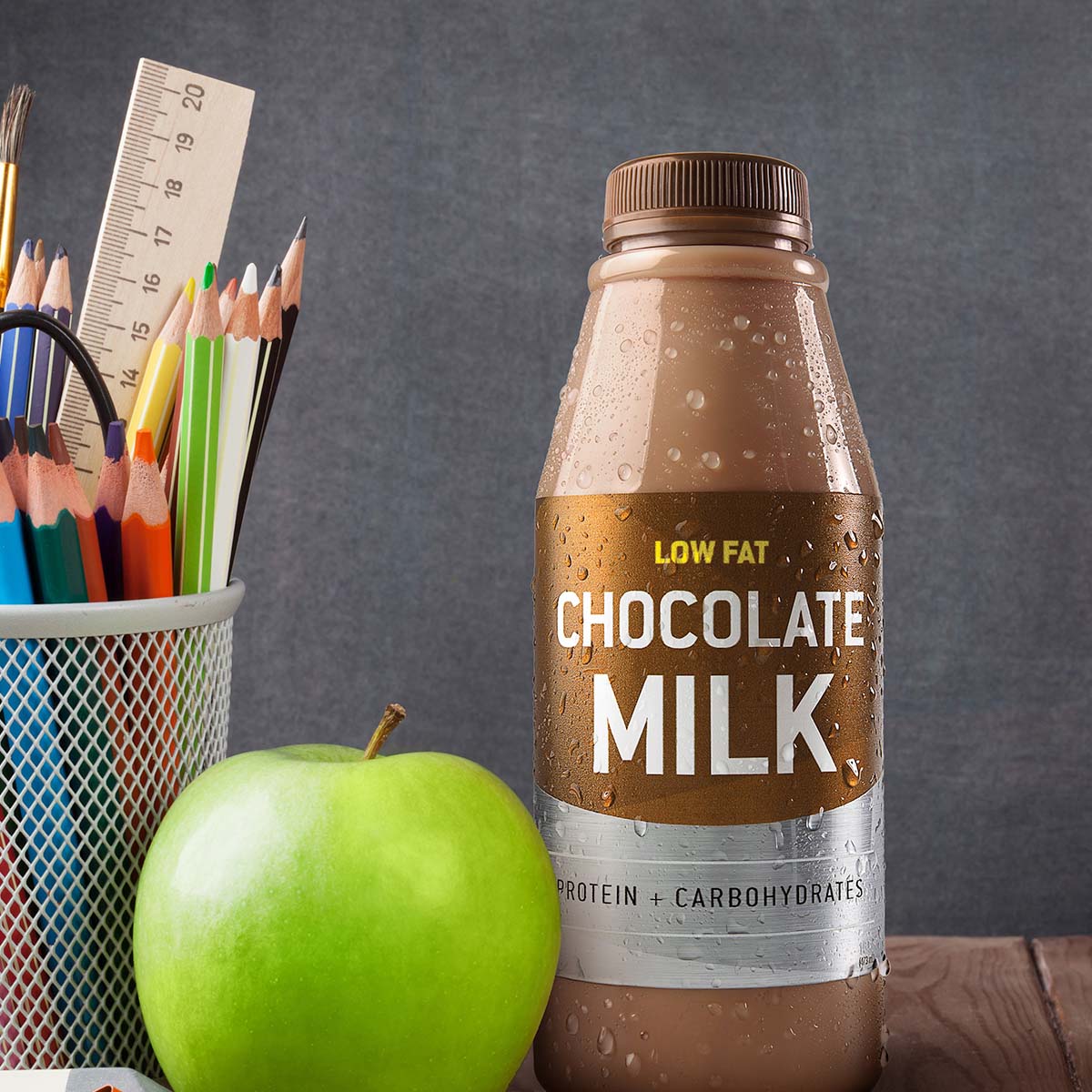 chocolate milk bottle next to an apple and school supplies