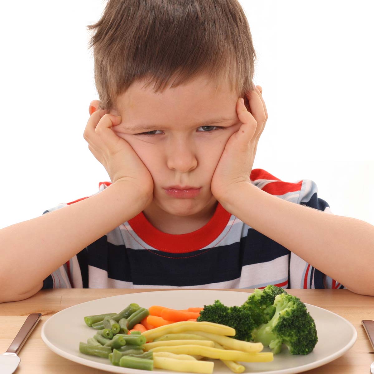 kid looking sad over a plate of veggies