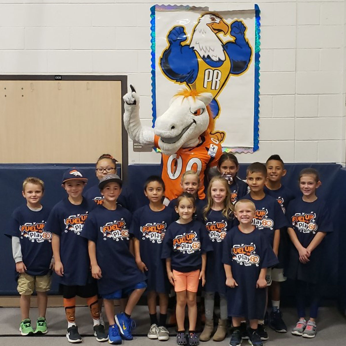 elementary students standing with Miles the mascot in a gym