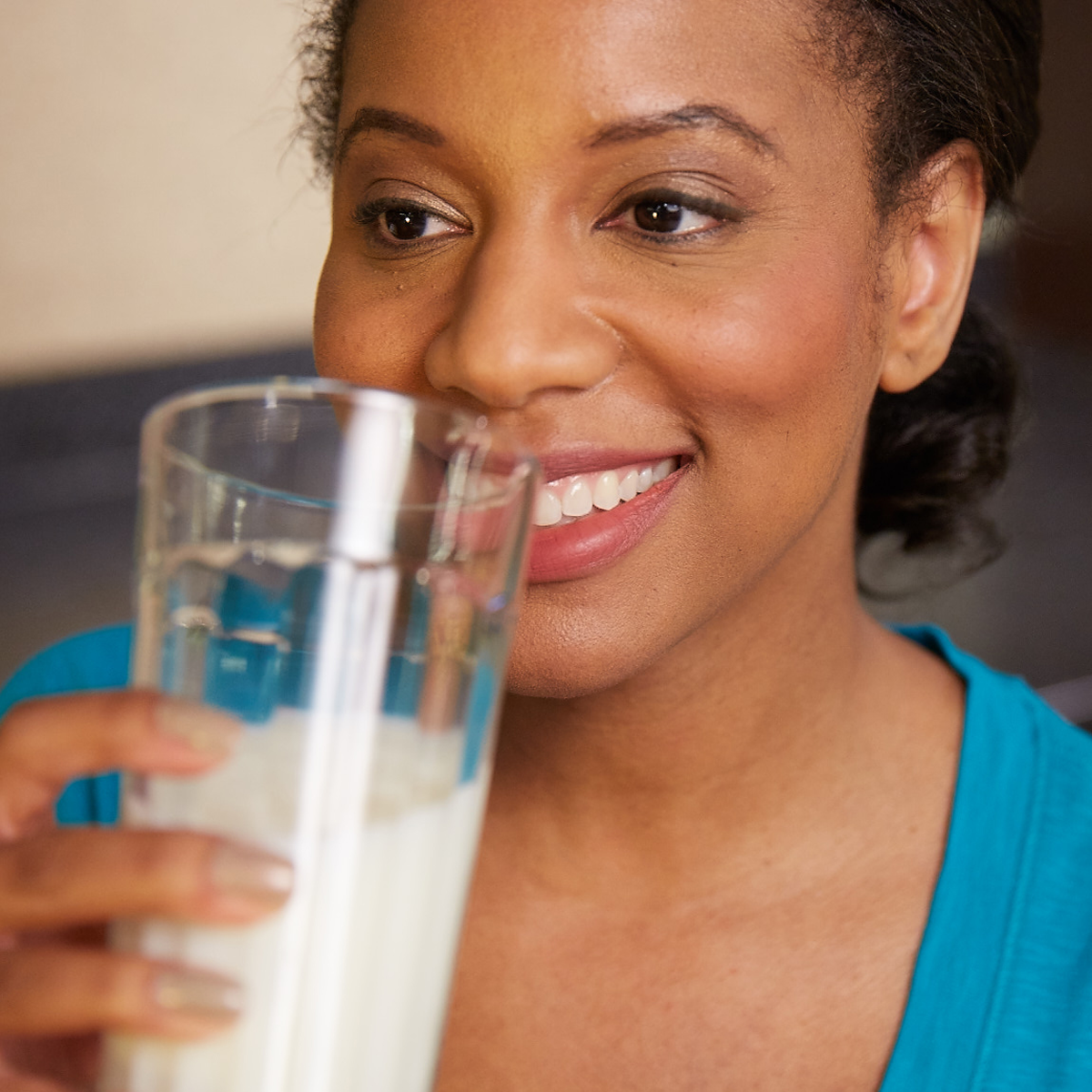 woman drinking a glass of milk and smiling