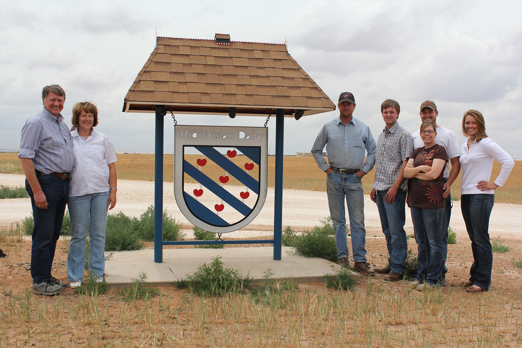 The van der Ploeg family poses with their dairy's sign.