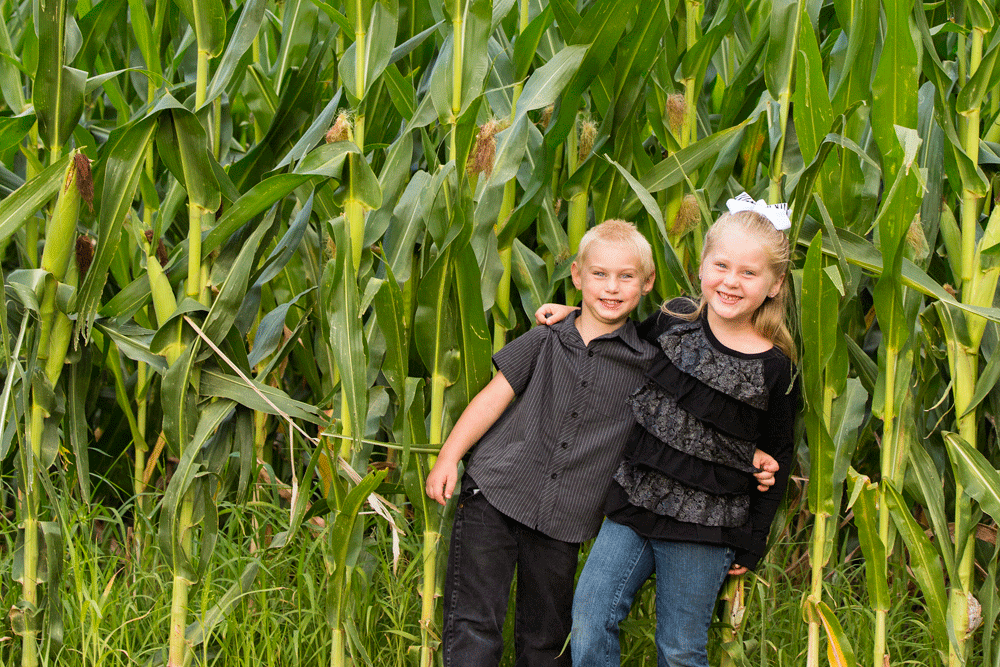 The youngest generation of Bernhardts poses in front of corn that will feed the herd.
