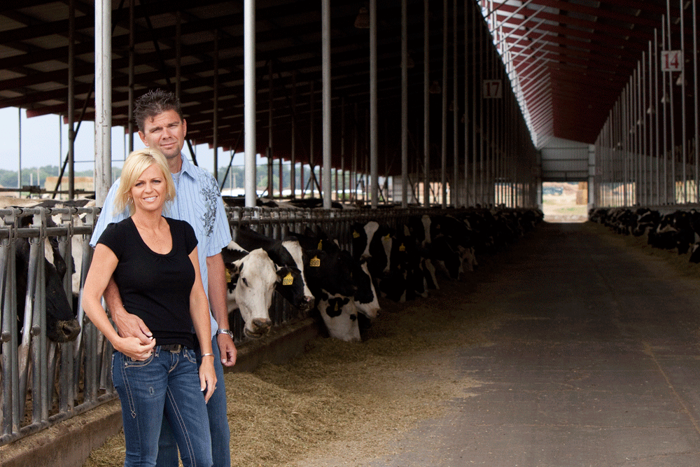 Norm and Britt Dinis pose in front of their barn full of Holstein cows.