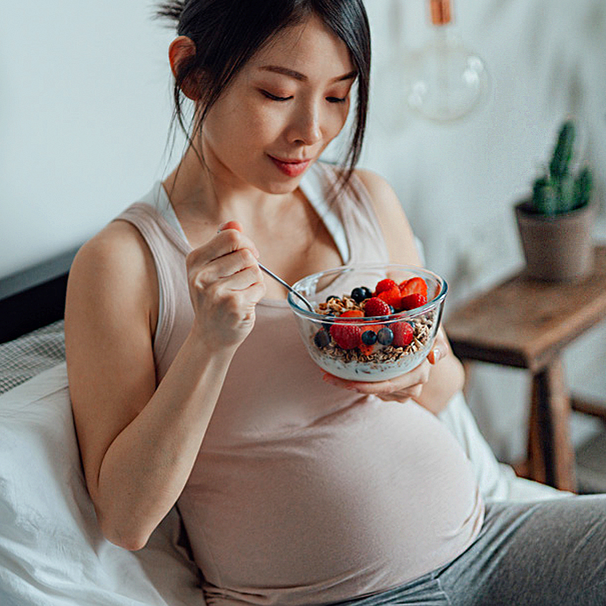 Pregnant woman eating a bowl of berries