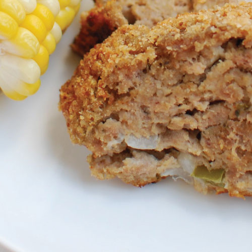 meatloaf slices on a plate with corn on the cob and green beans