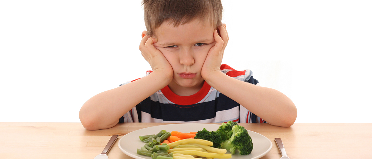 kid looking sad over a plate of veggies