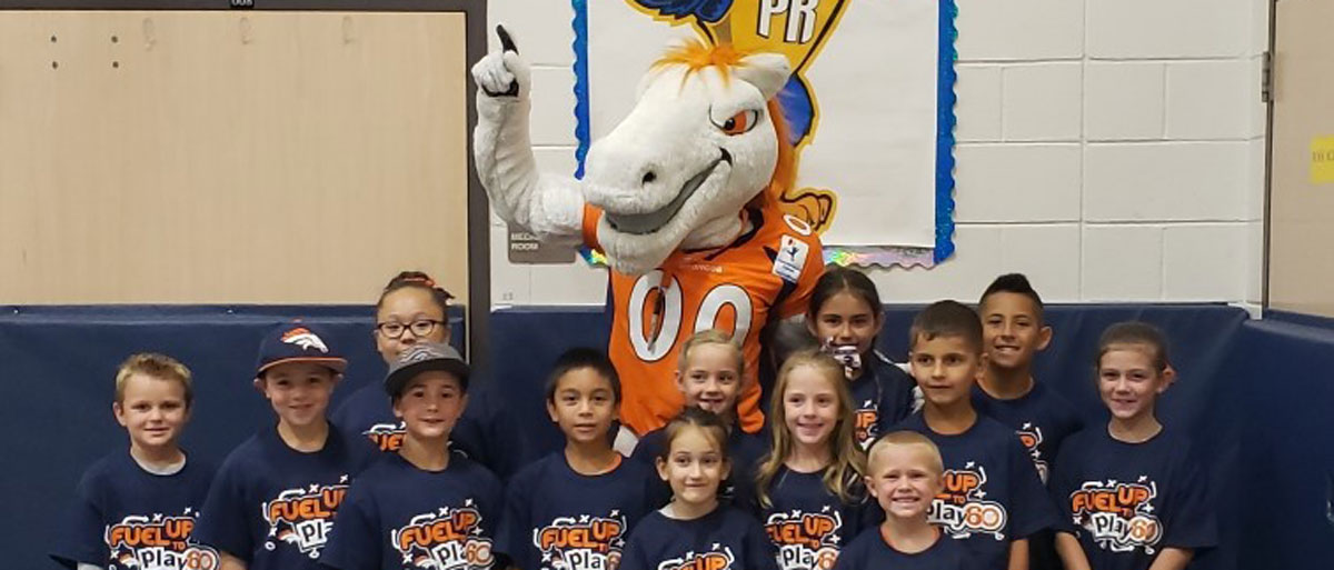 elementary students standing with Miles the mascot in a gym