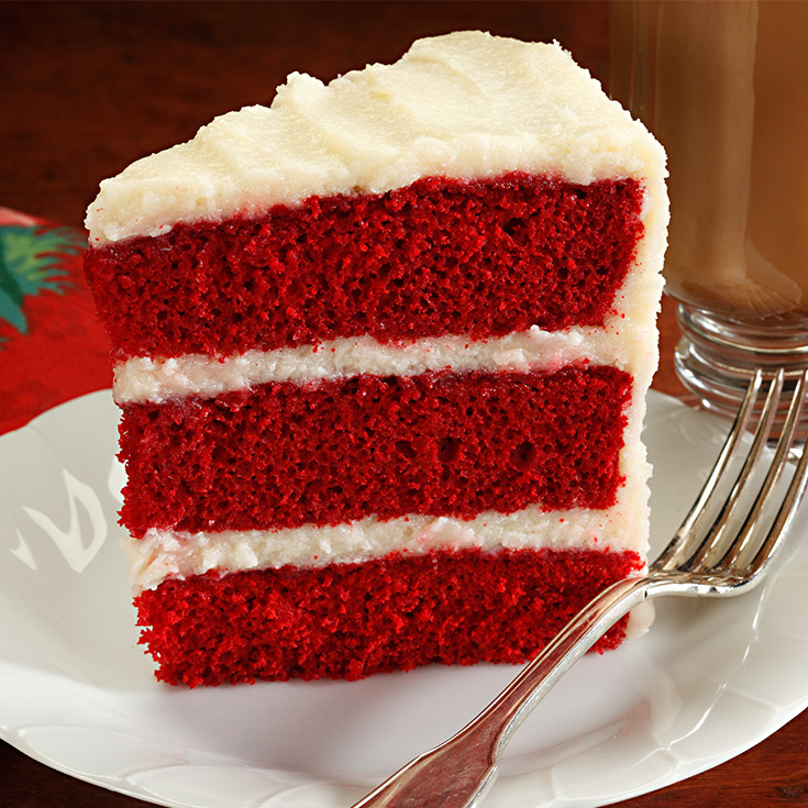 slice of red cake with 3 layers of white frosting