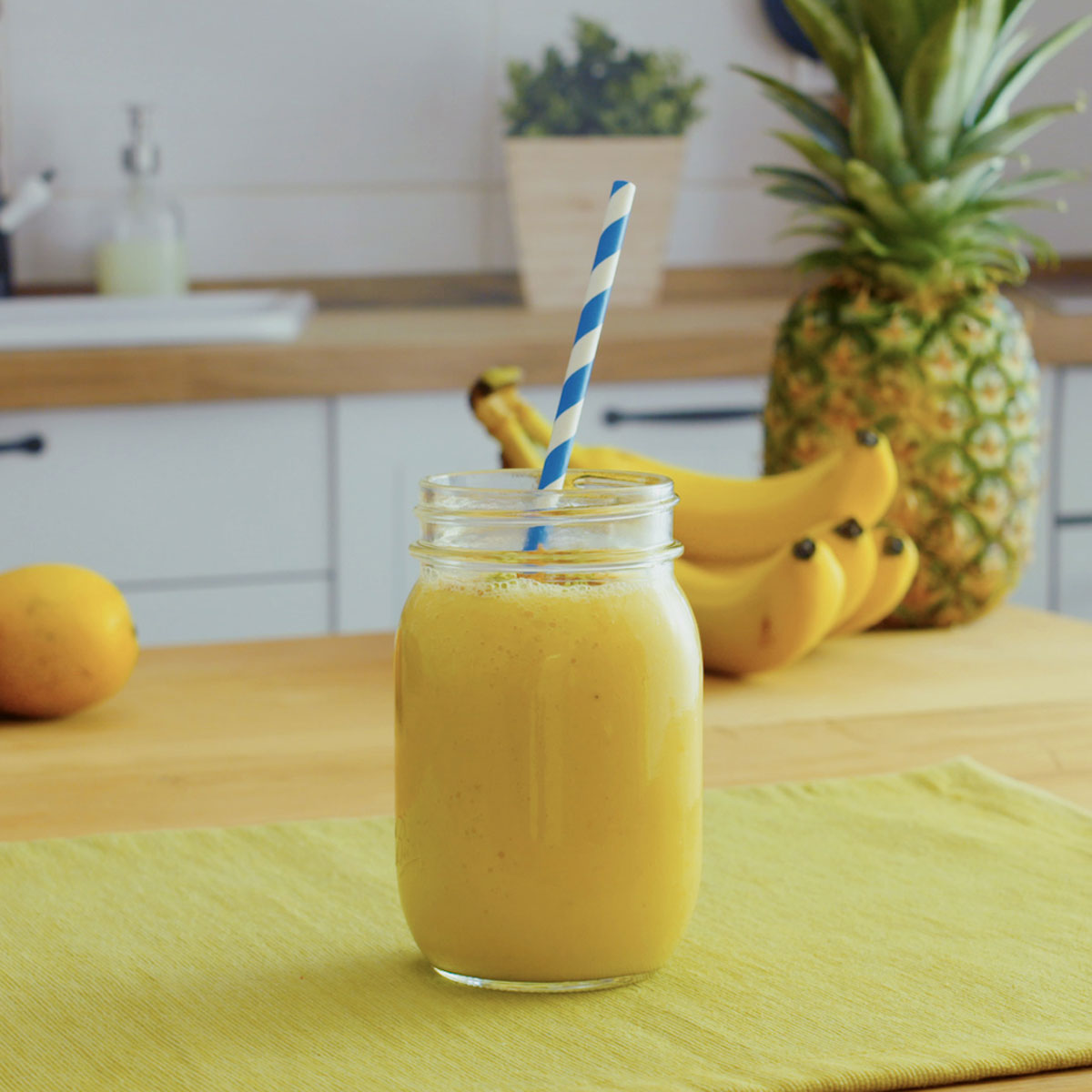 sunshine smoothie with pineapple, banana and mango in the background