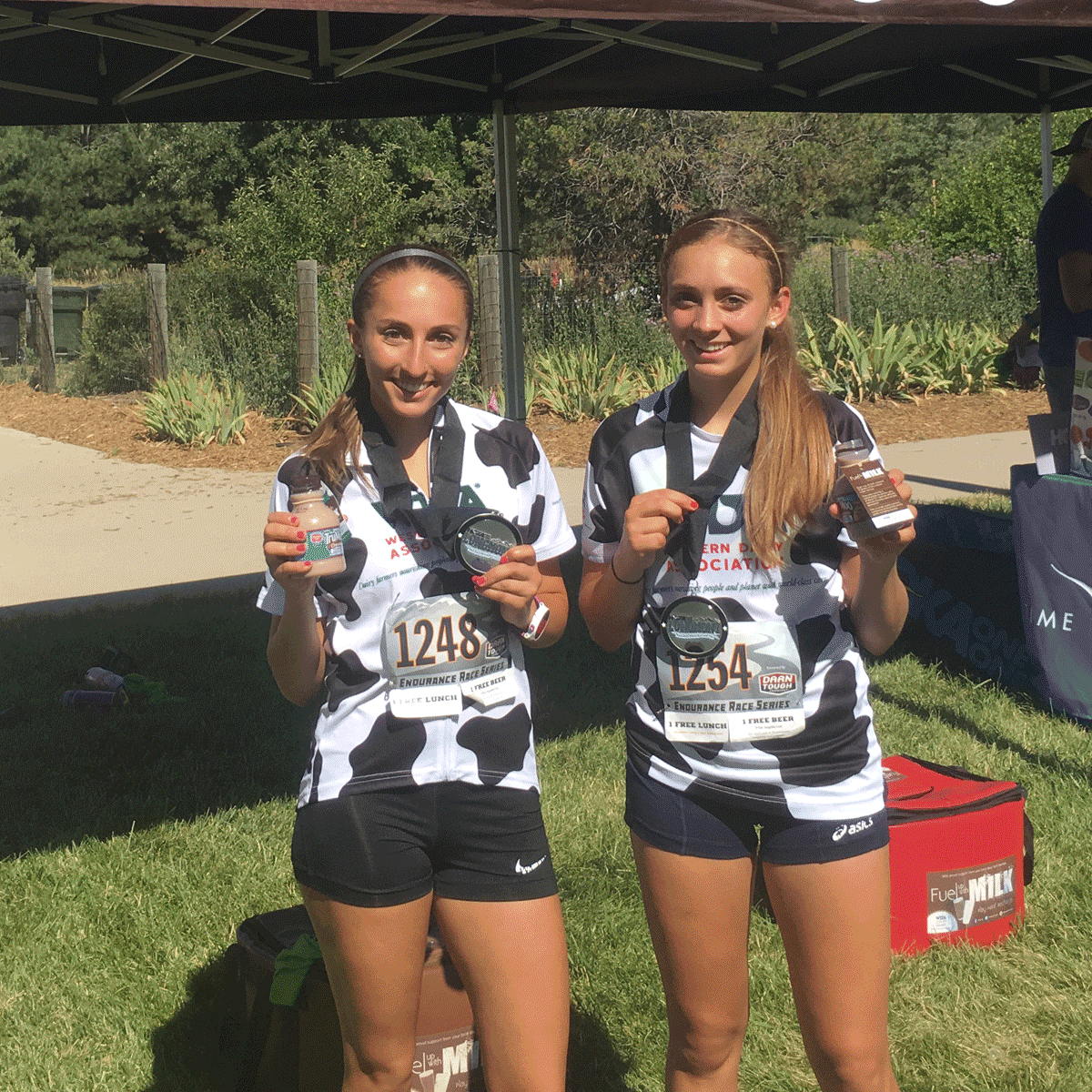 two young women in cow print running shirts smiling with chocolate milk